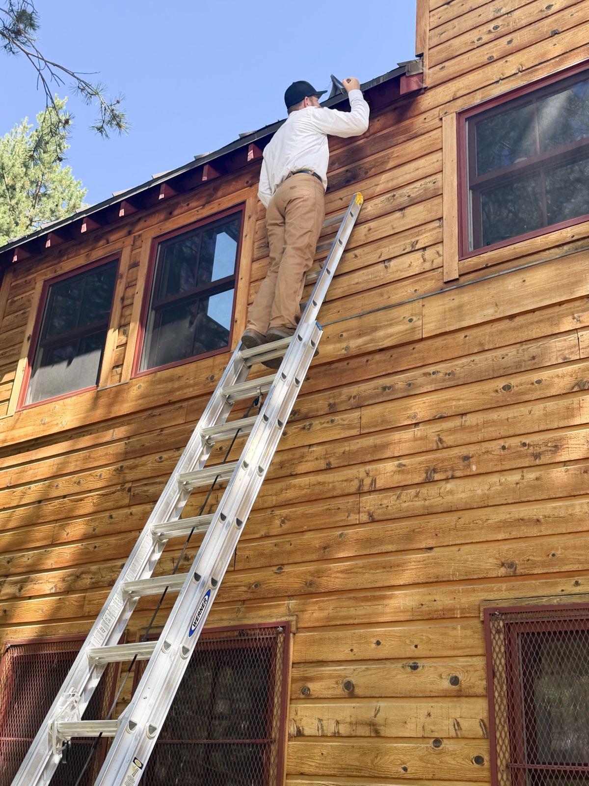 Ease owner Elliott Adams inspecting a roofline from a ladder at a Sacramento-area home